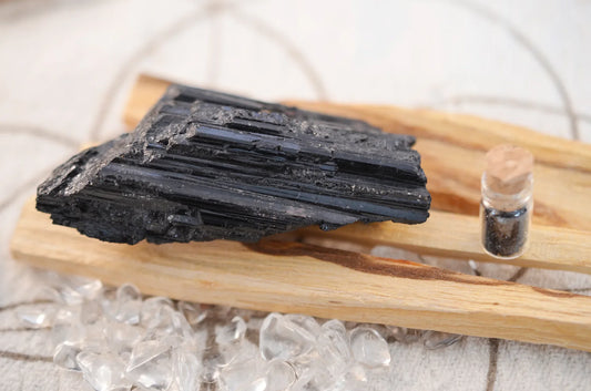 Minerai de tourmaline présenté sur une planche de bois et un facon rempli de minerai de tourmaline concassés.