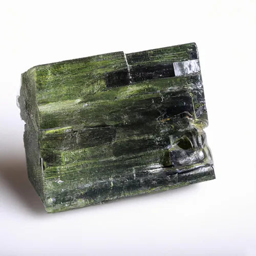 Minerai de tourmaline vert foncé sur un fond blanc.