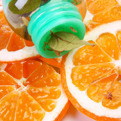 Bouchon vert sur un flacon transparent posé sur des tranches d'oranges fraîches.